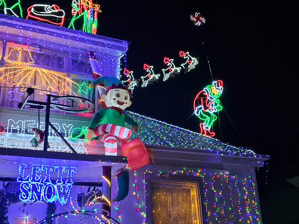 Johnnys Christmas Light Display decorated for Christmas with bright multicolored LED lights, string lights, inflatable ornaments, and holiday-themed light displays at night under a dark sky.